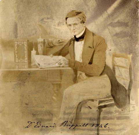Eine Gemälde zeigt Edouard Rüppell sitzend eine Zeitungs lesend im Jahr 1846