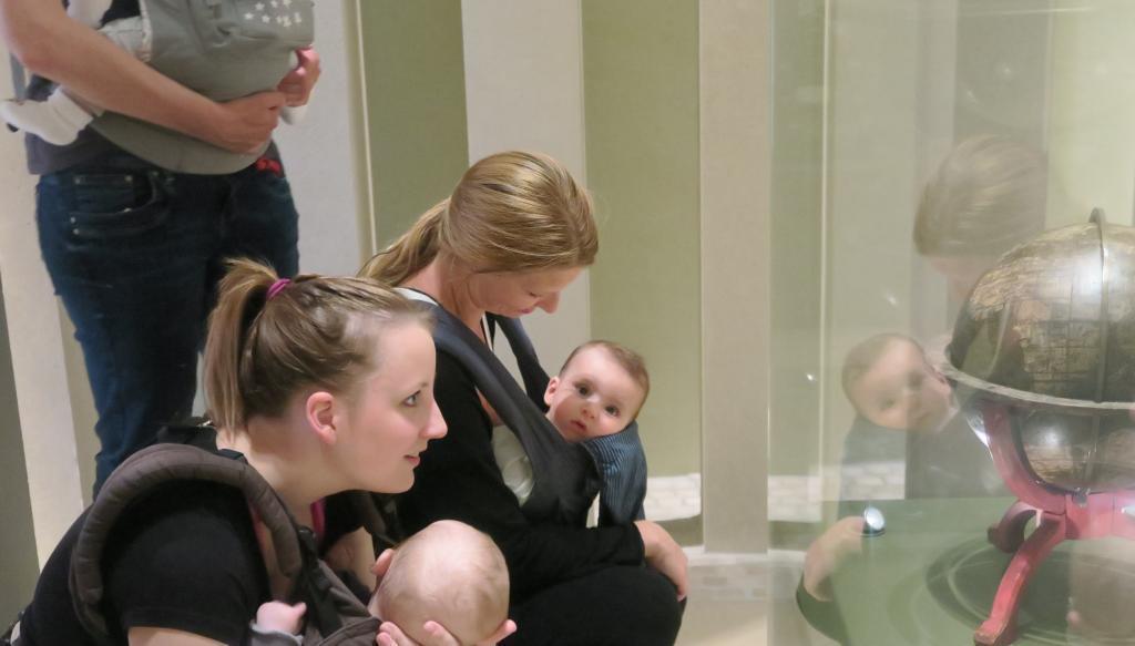 Frauen mit Babys vor Ausstellungsobjekt 