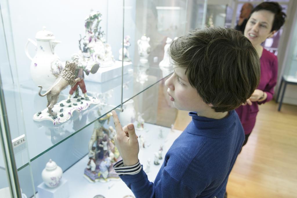 Junger Besucher betrachtet Porzellanfigur in einer Vitrine des Porzellanmuseums