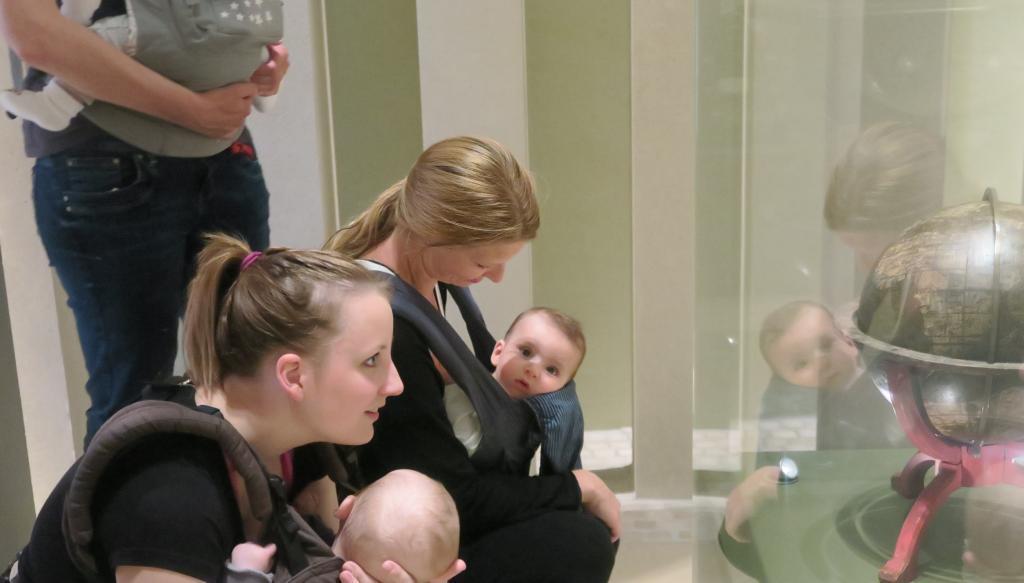 Manduca Führung (c) HMF Auf dem Bild sieht man eine Gruppe von Müttern mit Kleinkindern, die fasziniert in eine Vitrine blicken. (c) HMF