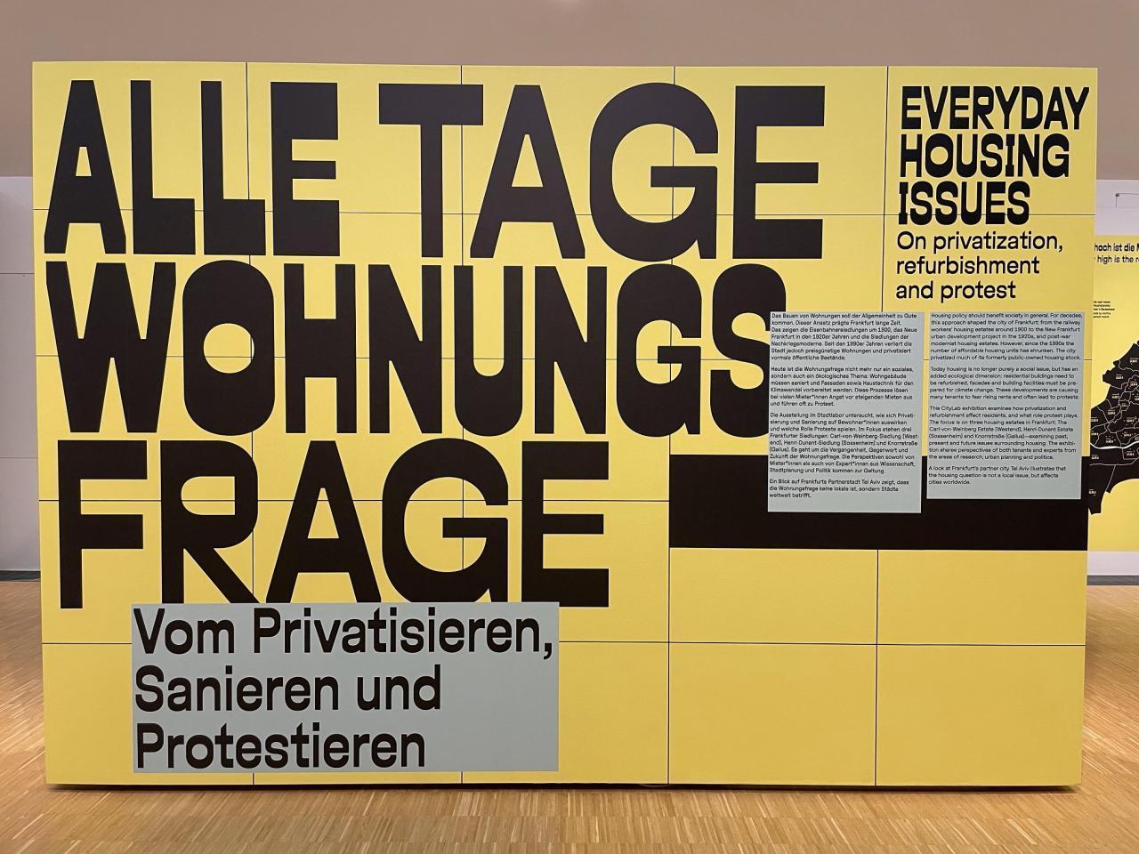 Eine gelbe Ausstellungswand mit dem Titel Alle Tage Wohnungsfrage