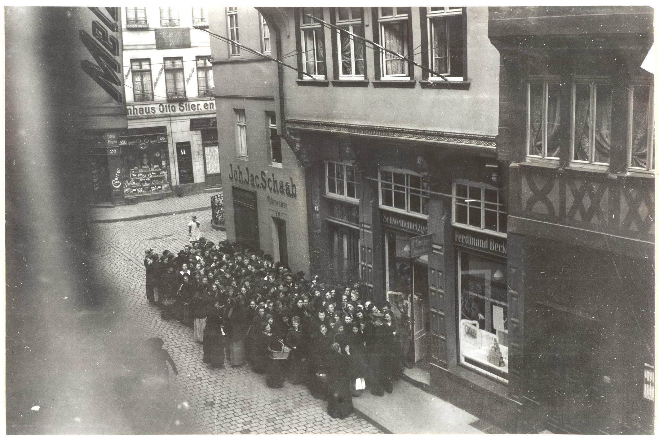 Das historische Foto zeigt eine Personengruppe vor einem Geschäft in der Frankfurter Altstadt um 1916.